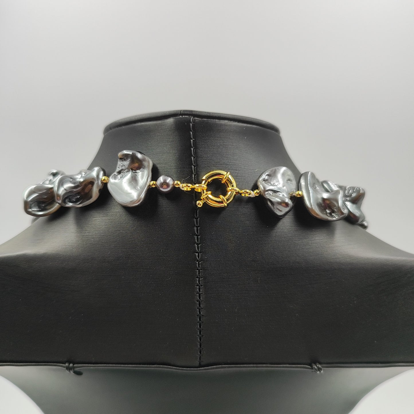 Chiusura in ottone placcato oro e perle irregolari grigio scuro con perle distanziatrici oro.