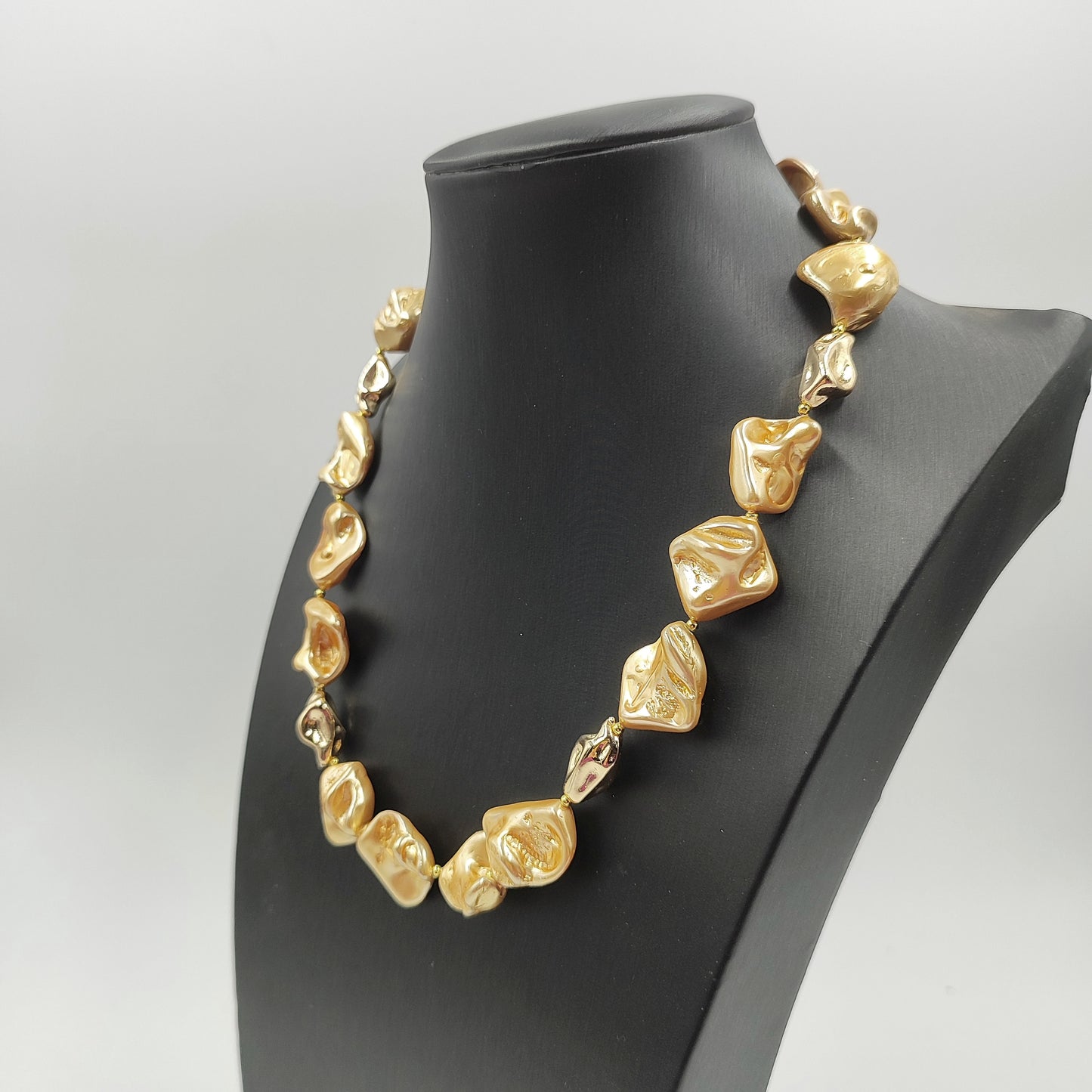 Dettaglio di perle irregolari color pesca e perle color oro lucide. 