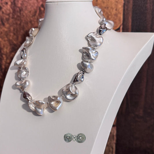 Dettaglio alternanza perle barocche bianche e argento con riflessi metallici.