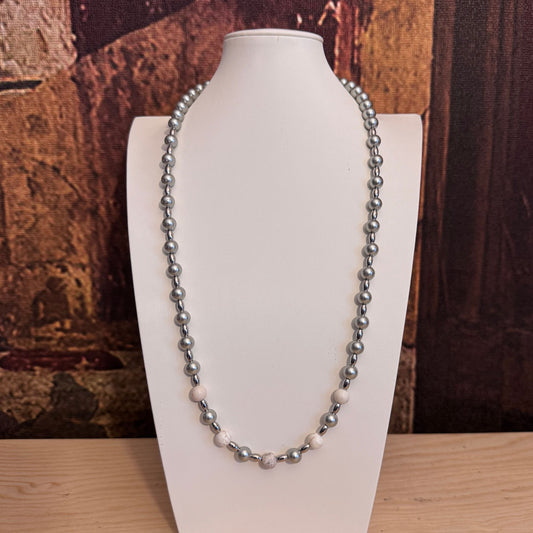 Dettaglio accostamento perla di conchiglia grigia e howlite naturale venata.