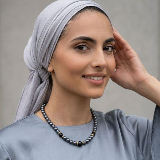Modella con foulard che indossa girocollo grigio perle elegance con dettagli oro e perle nere centrali 