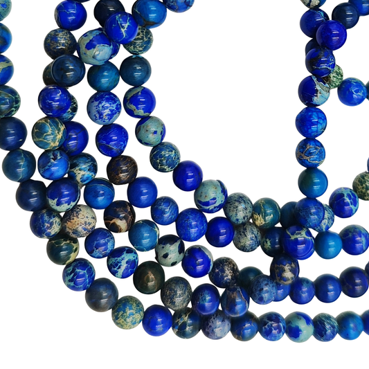 Primo piano del filo di Diaspro Imperiale Blu, perle lisce 6 mm, che mostrano le varie tonalità di blu e le venature chiare.