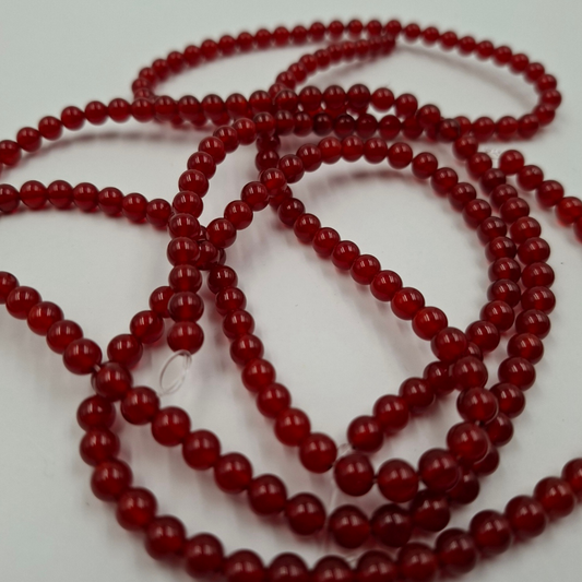 Dettaglio macro di una perla di Agata Rossa 6mm, che mostra la finitura liscia e la lucentezza 