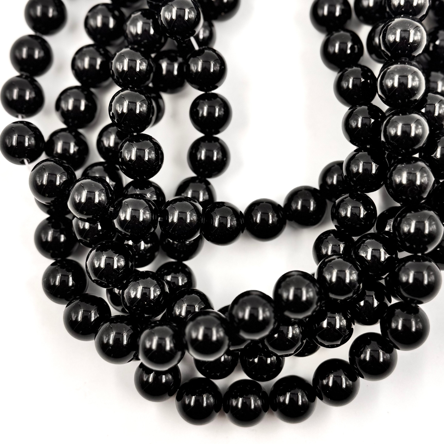 Primo piano delle perle, che mostra il nero intenso e la qualità della lucidatura (Pietra Aurea).