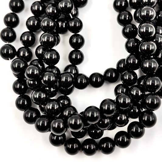 Primo piano delle perle, che mostra il nero intenso e la qualità della lucidatura (Pietra Aurea).