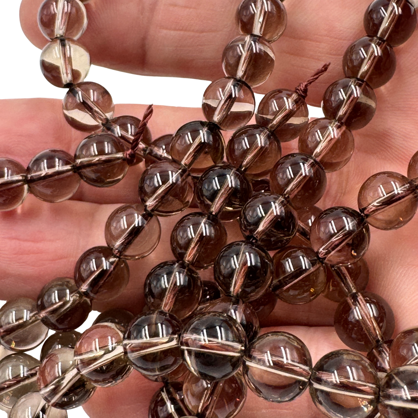 Scatto macro di perle tonde di Quarzo Fumè Grado AA, la pietra che neutralizza la negatività.