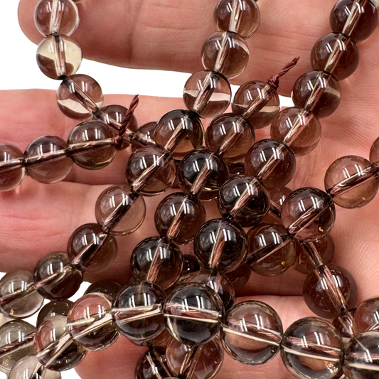 Scatto macro di perle tonde di Quarzo Fumè Grado AA, la pietra che neutralizza la negatività.