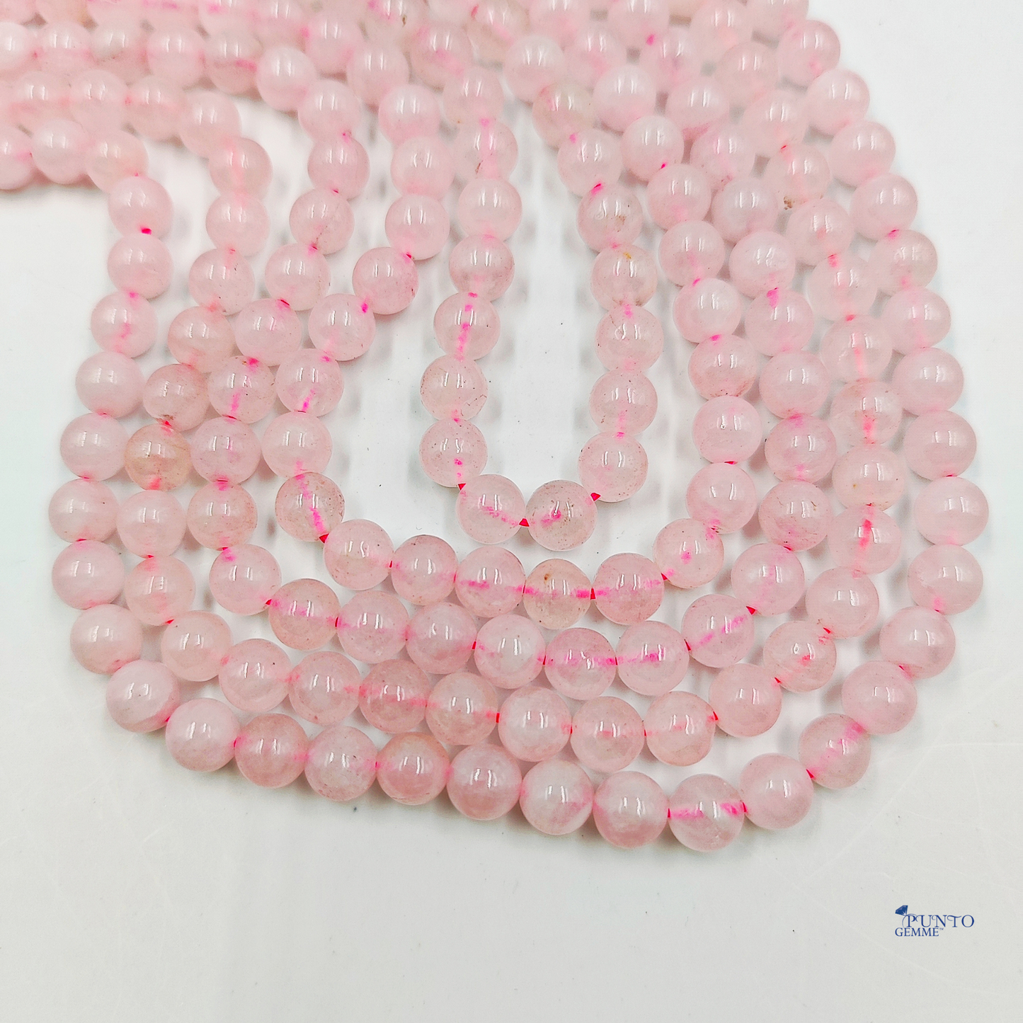 Fili di Quarzo Rosa 6mm disteso su uno sfondo che richiama la delicatezza e l'amore.