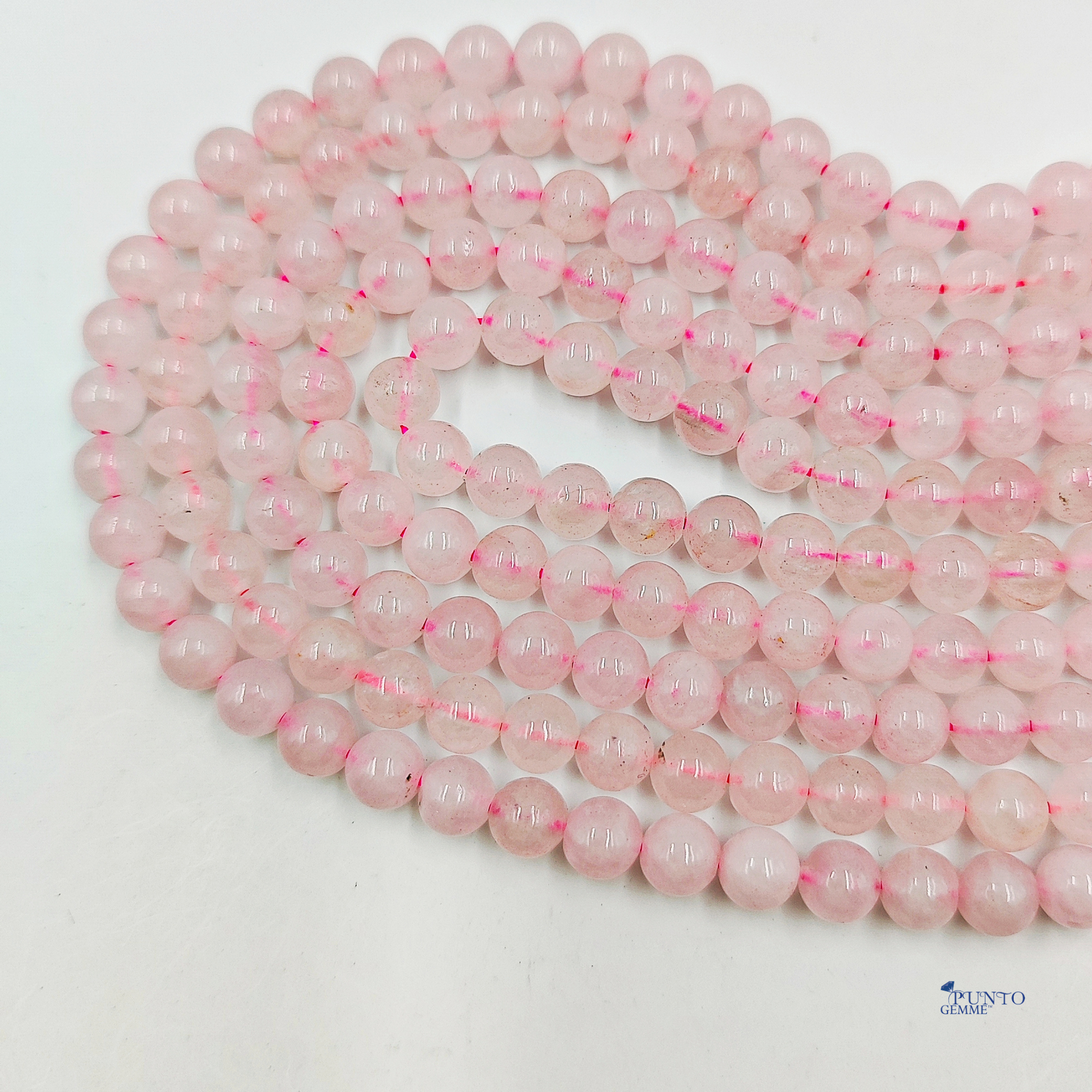 Dettaglio macro di una perla di Quarzo Rosa 6mm, che evidenzia la traslucidità e la texture lattiginosa.