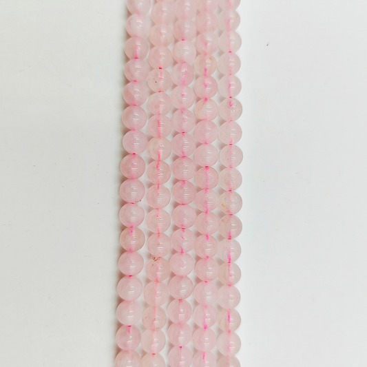 Primo piano del filo di Quarzo Rosa 6mm, che mostra il colore rosa pallido e la finitura liscia.