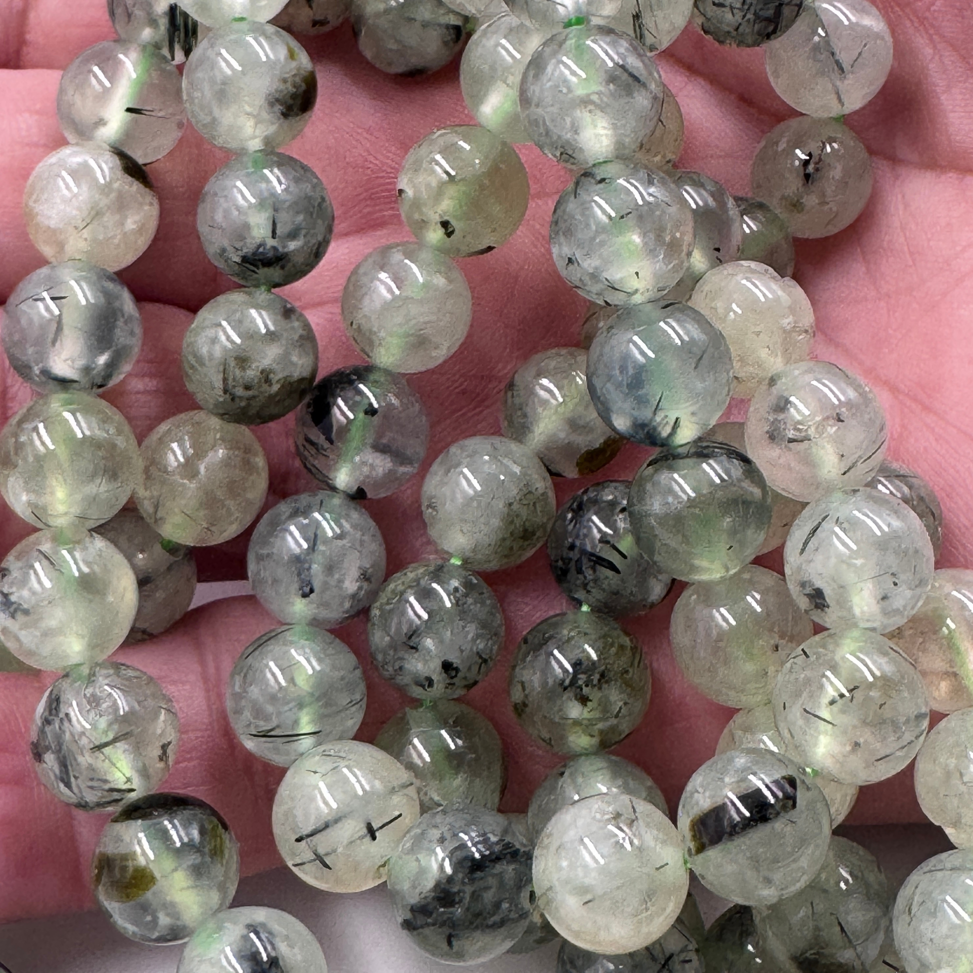 Dettaglio ravvicinato delle perle in Prehnite (PE0813-08) di 8 mm, che evidenzia la finitura lucida e la trasparenza della gemma.