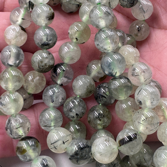 Dettaglio ravvicinato delle perle in Prehnite (PE0813-08) di 8 mm, che evidenzia la finitura lucida e la trasparenza della gemma.