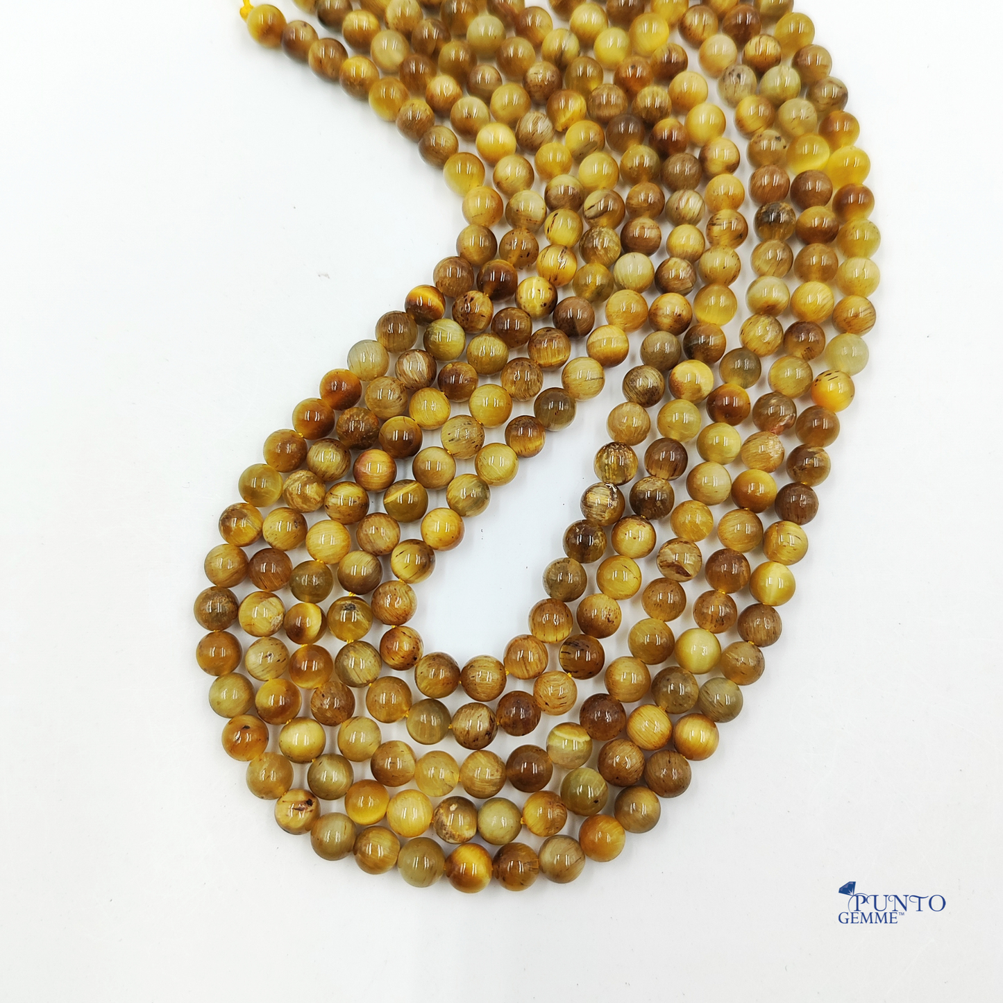 Fili di Occhio di Tigre Gold distesi su uno sfondo bianco per enfatizzare la lucentezza setosa