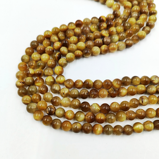 Primo piano del filo di Occhio di Tigre Gold 6mm, che mostra le vivaci bande dorate dell'effetto gatteggiamento.