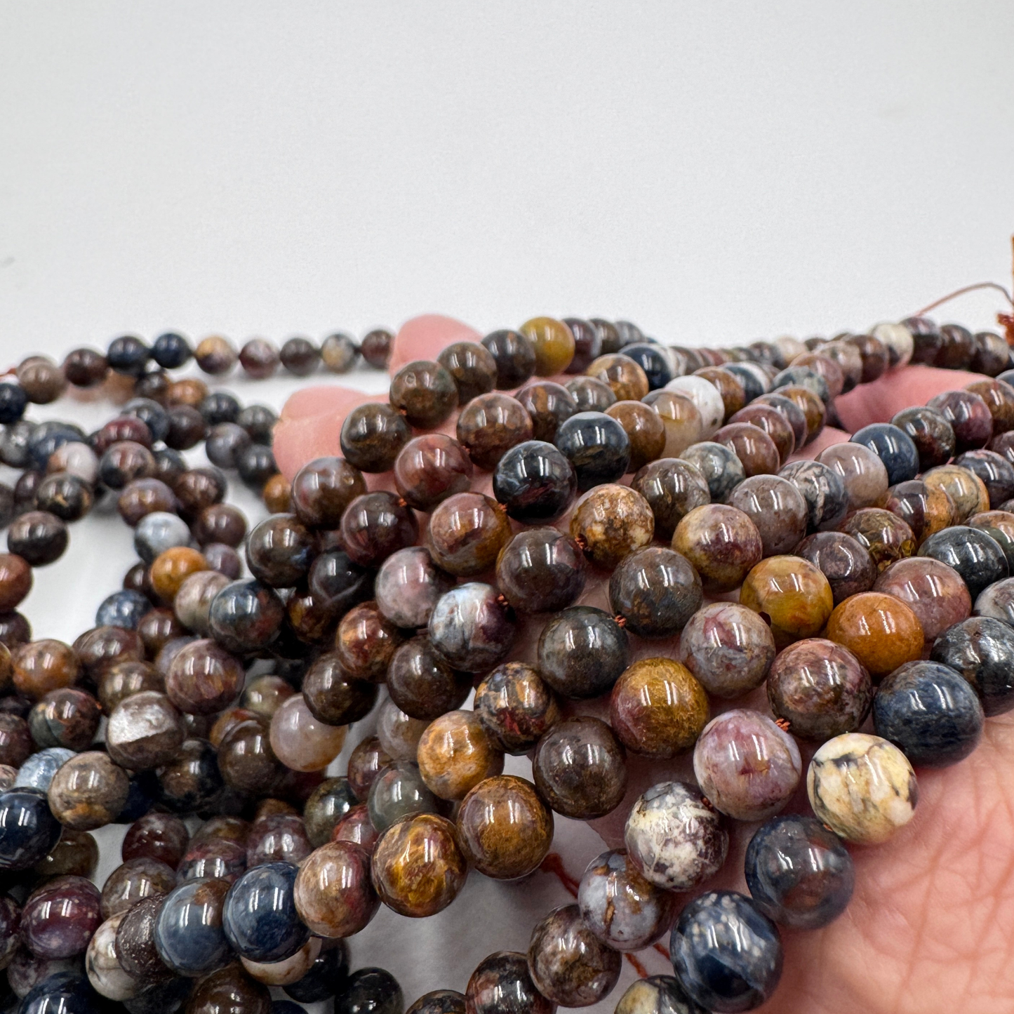 Filo di perle sferiche lisce di Pietersite naturale da 6 mm, con il pattern dinamico di blu e oro e l'effetto chatoyance.