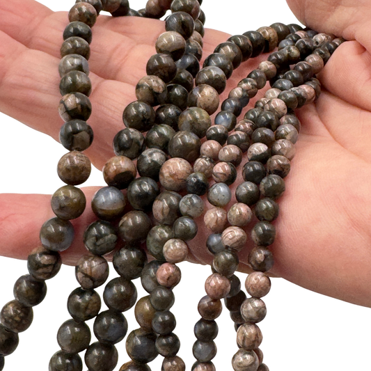 Dettaglio ravvicinato delle perle in Glaucofane (PE0925-04) di 4 mm, che evidenzia la finitura lucida e la trama opaca del minerale.