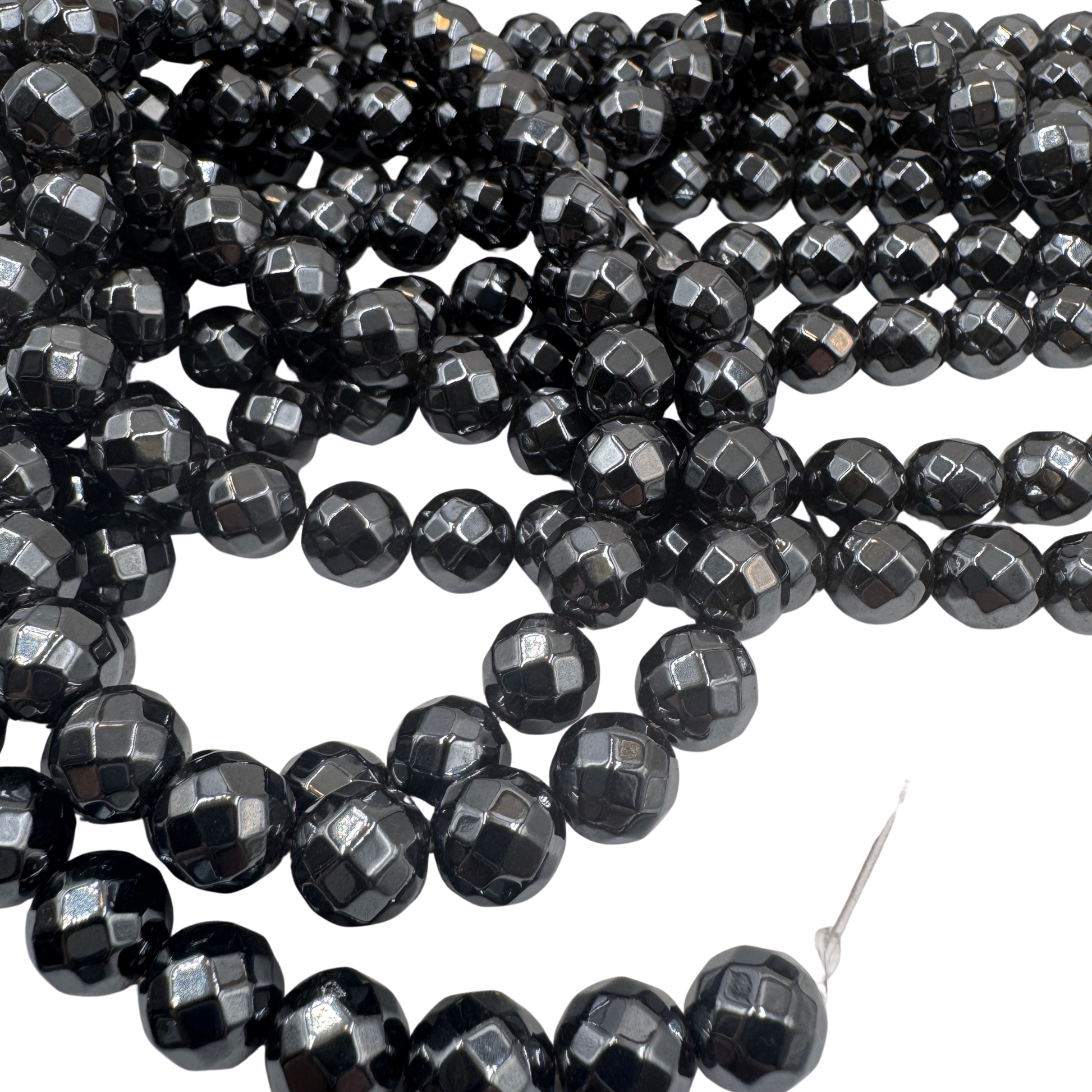 Primo piano del filo di Ematite sfaccettata 10mm, che mostra la finitura metallica e i riflessi del taglio.