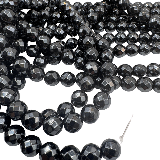 Primo piano del filo di Ematite sfaccettata 10mm, che mostra la finitura metallica e i riflessi del taglio.