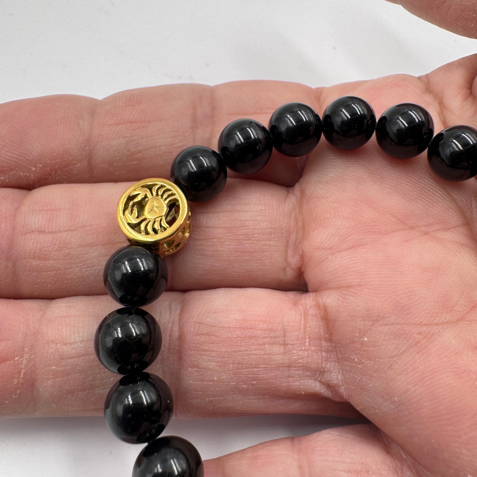 Dettaglio ravvicinato delle perle di Tormalina Nera lucida del bracciale Cancro.