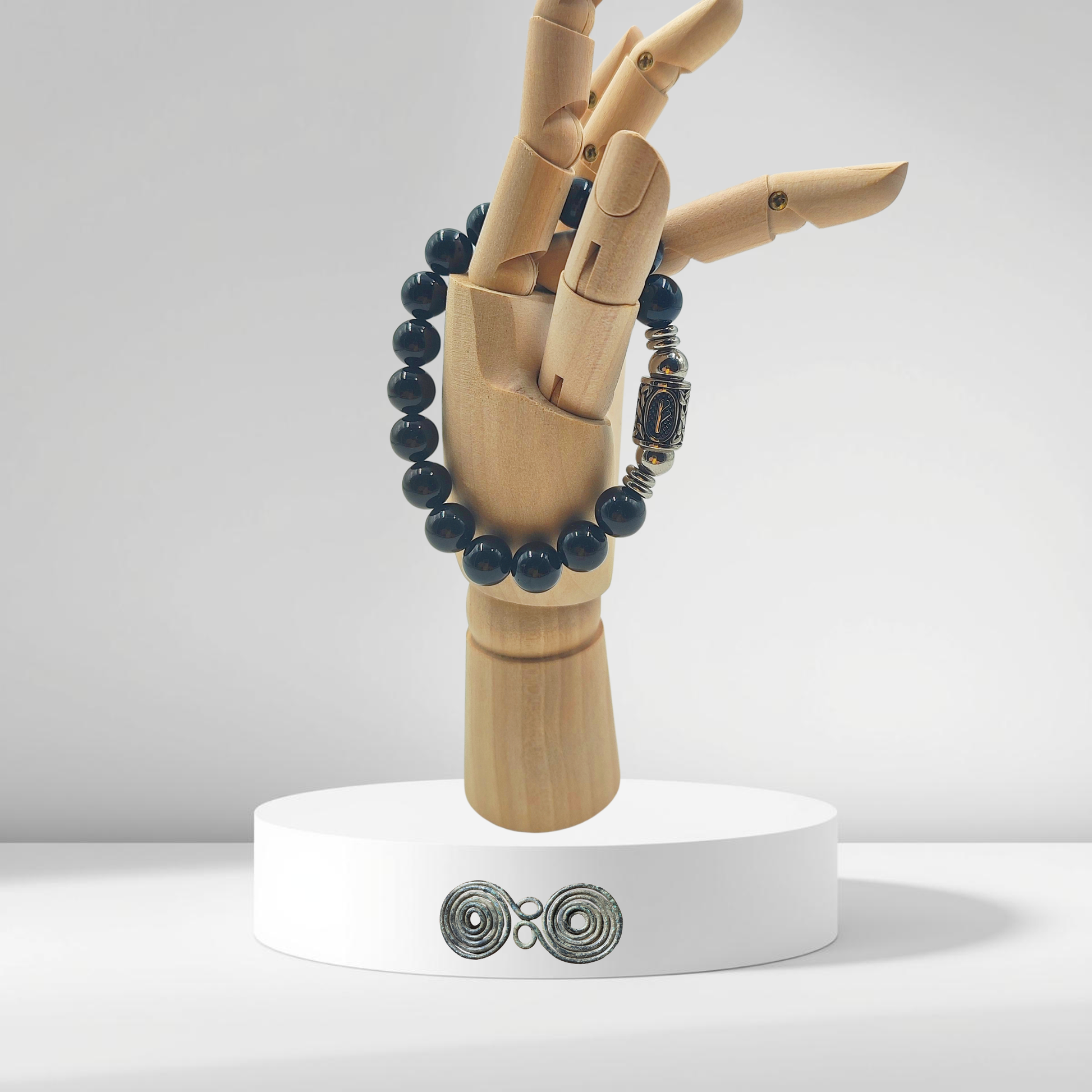 Bracciale in Tormalina Nera PE8041 con la runa Fehu incisa su una perla centrale, su mano in legno