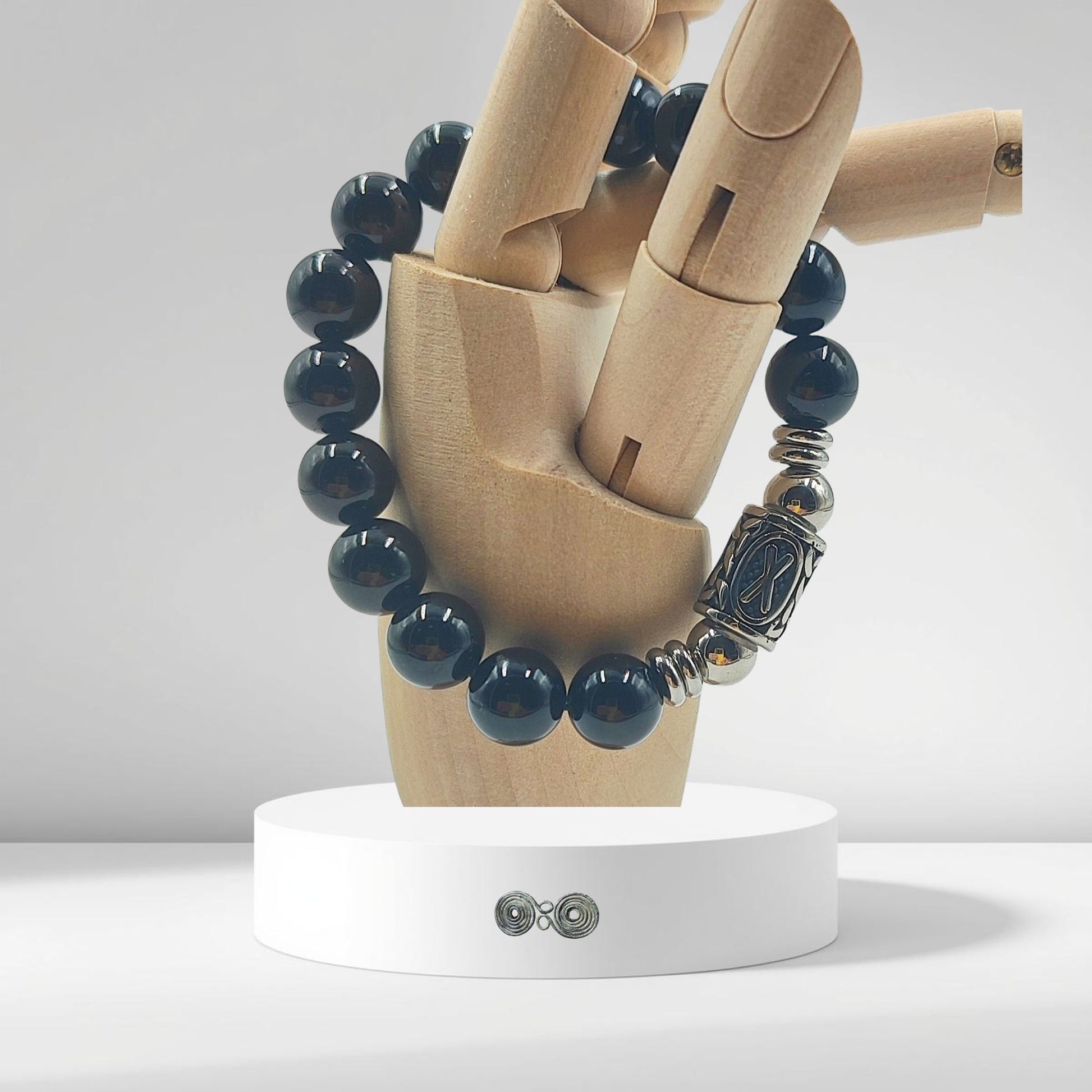 Primo piano incisione Runa Gebo (X) su acciaio inox e pietra nera naturale su mano legno.