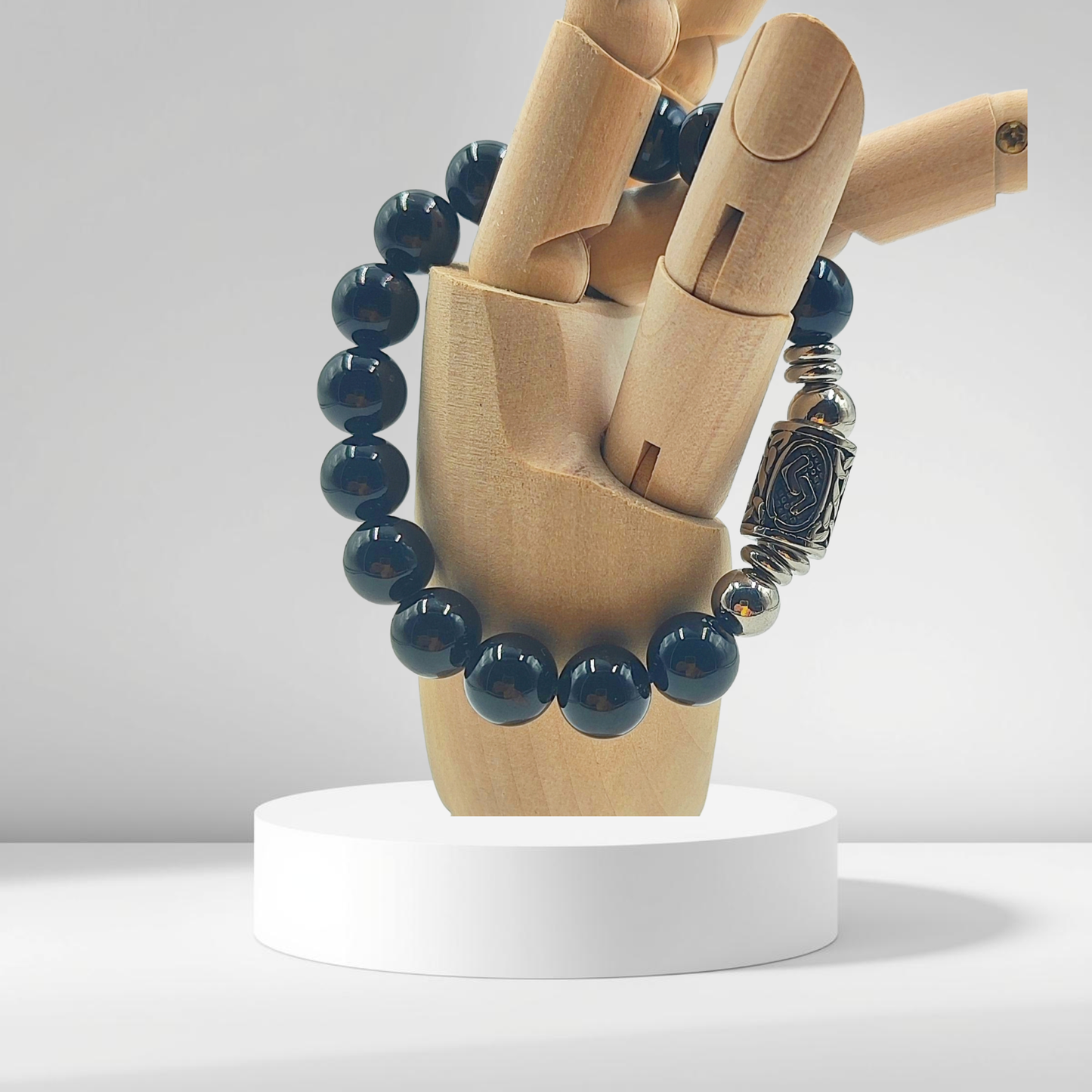 Vista ravvicinata delle perle nere lucide del bracciale PE8052, qualità lotto certificato su modello in legno