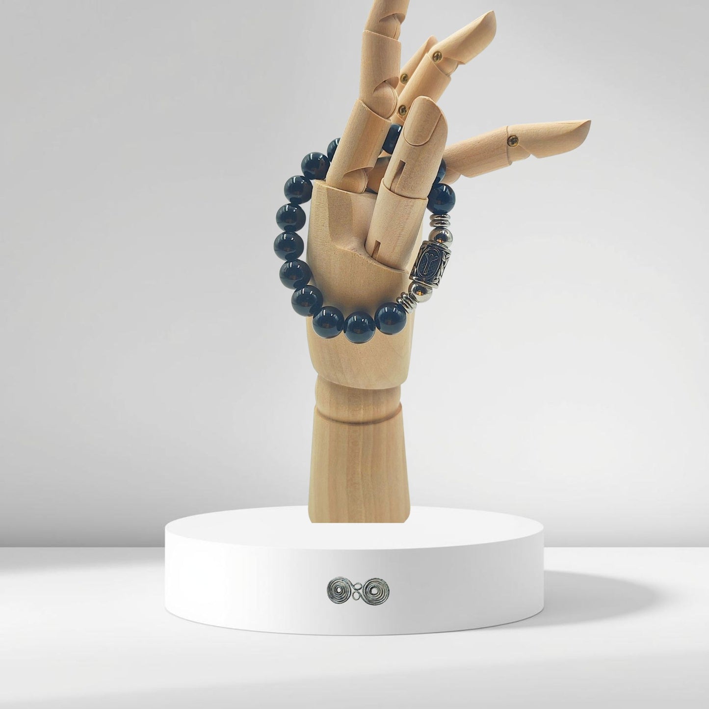 Bracciale Runa Algiz PE8055 indossato su polso in legno che evoca forza e protezione.