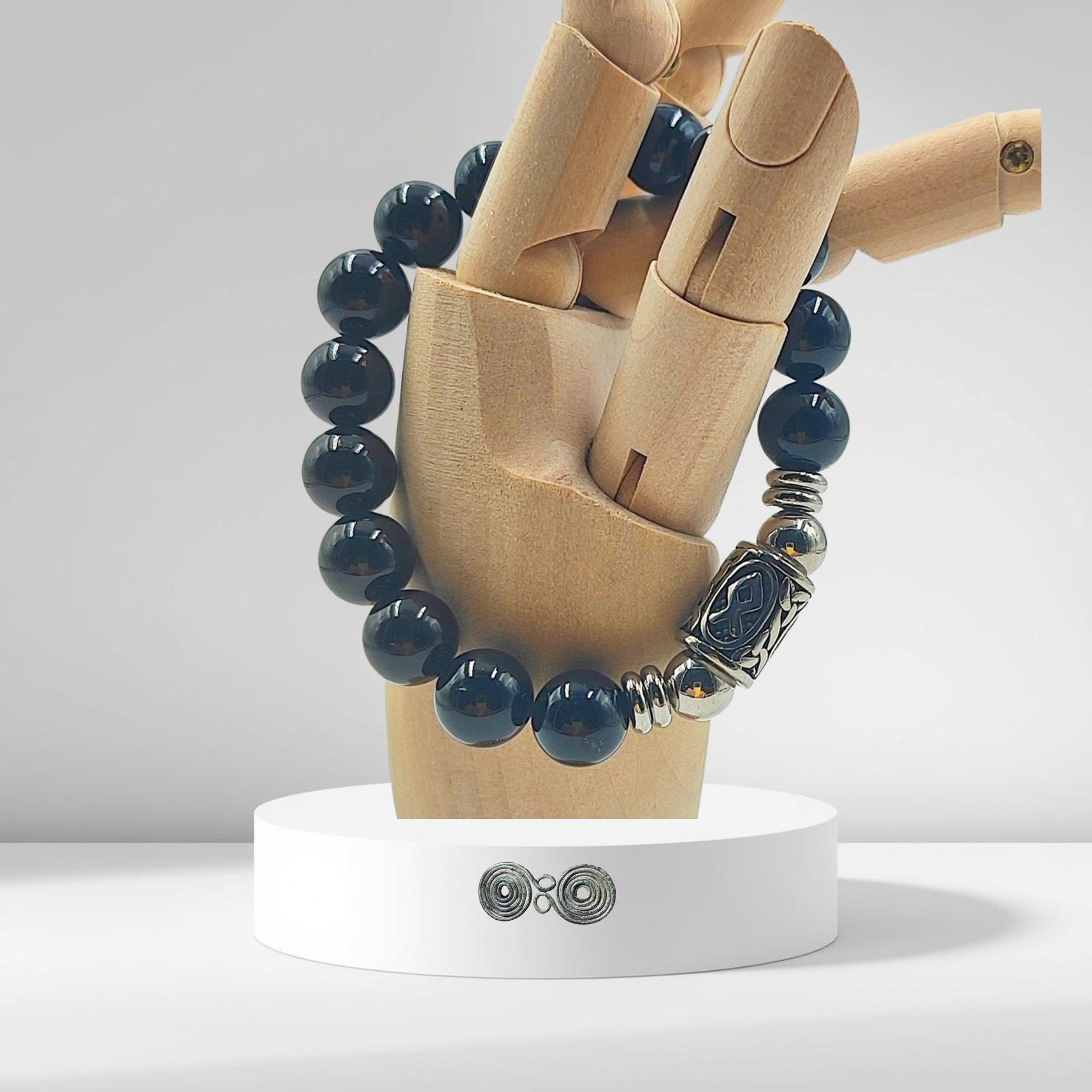 Primo piano incisione Runa Othala su acciaio inox e pietra nera naturale. su modello in legno